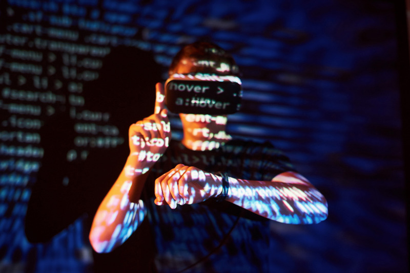 Double exposure of a caucasian man and Virtual reality VR headset is presumably a gamer or a hacker cracking the code into a secure network or server, with lines of code